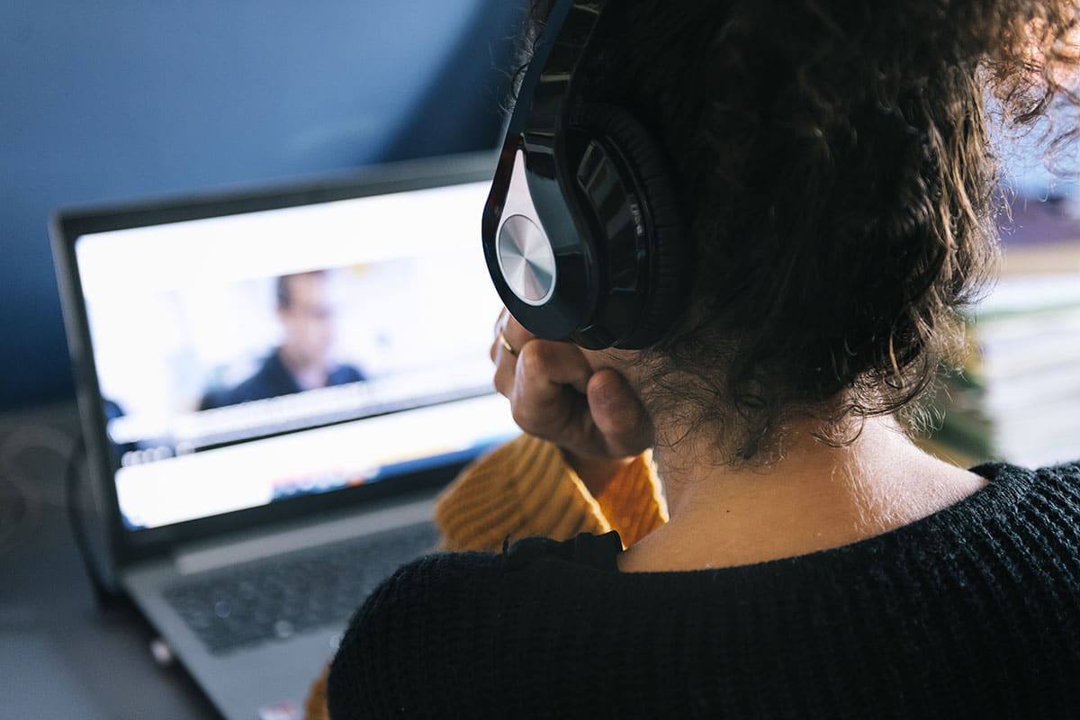 person watching video on laptop with headphones
