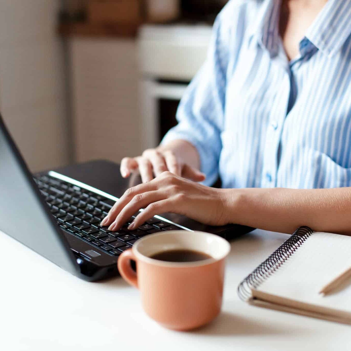 Freelancer workplace with laptop, cup of coffee and notebook.