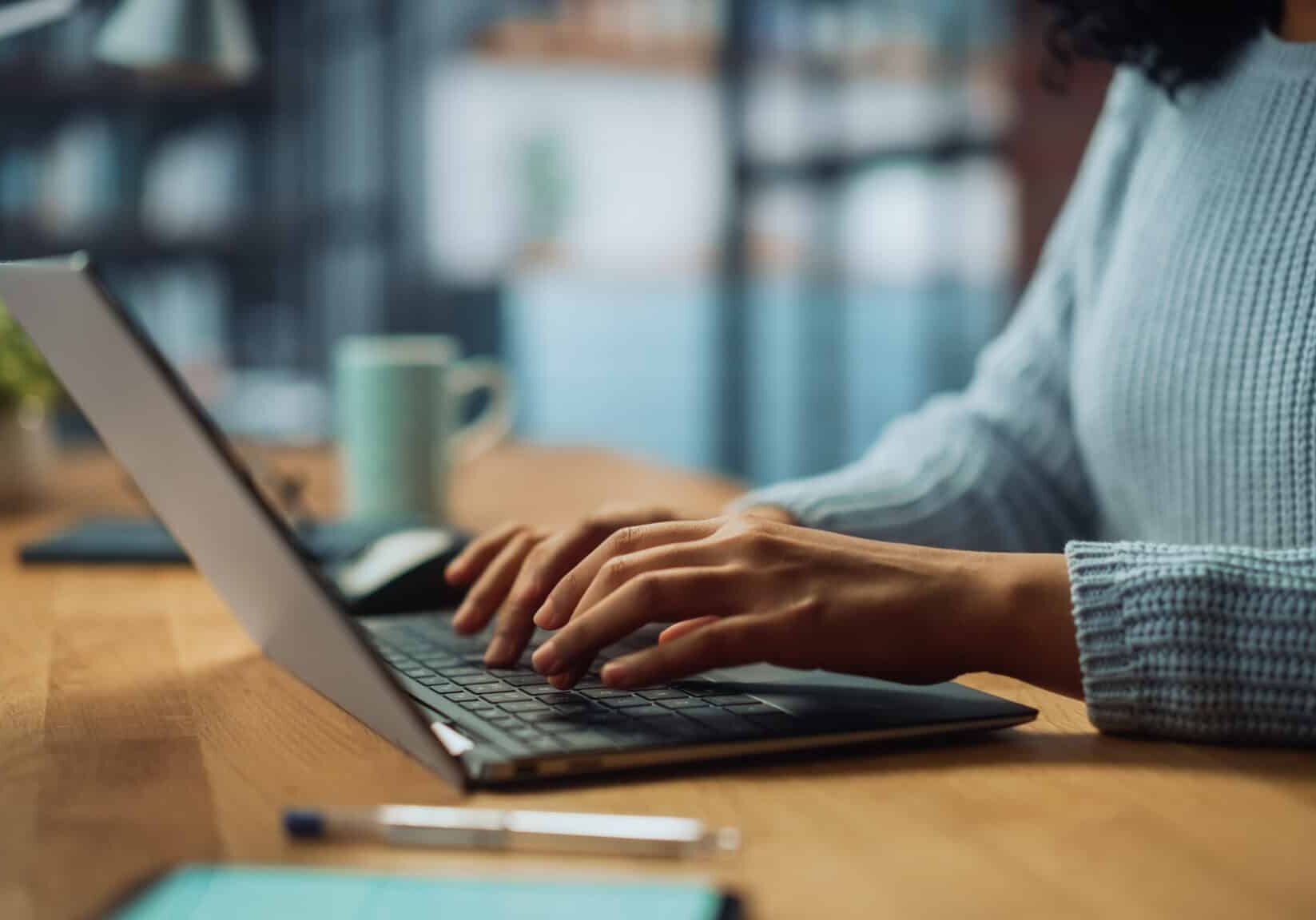 close up on hands of a female specialist working on laptop compu