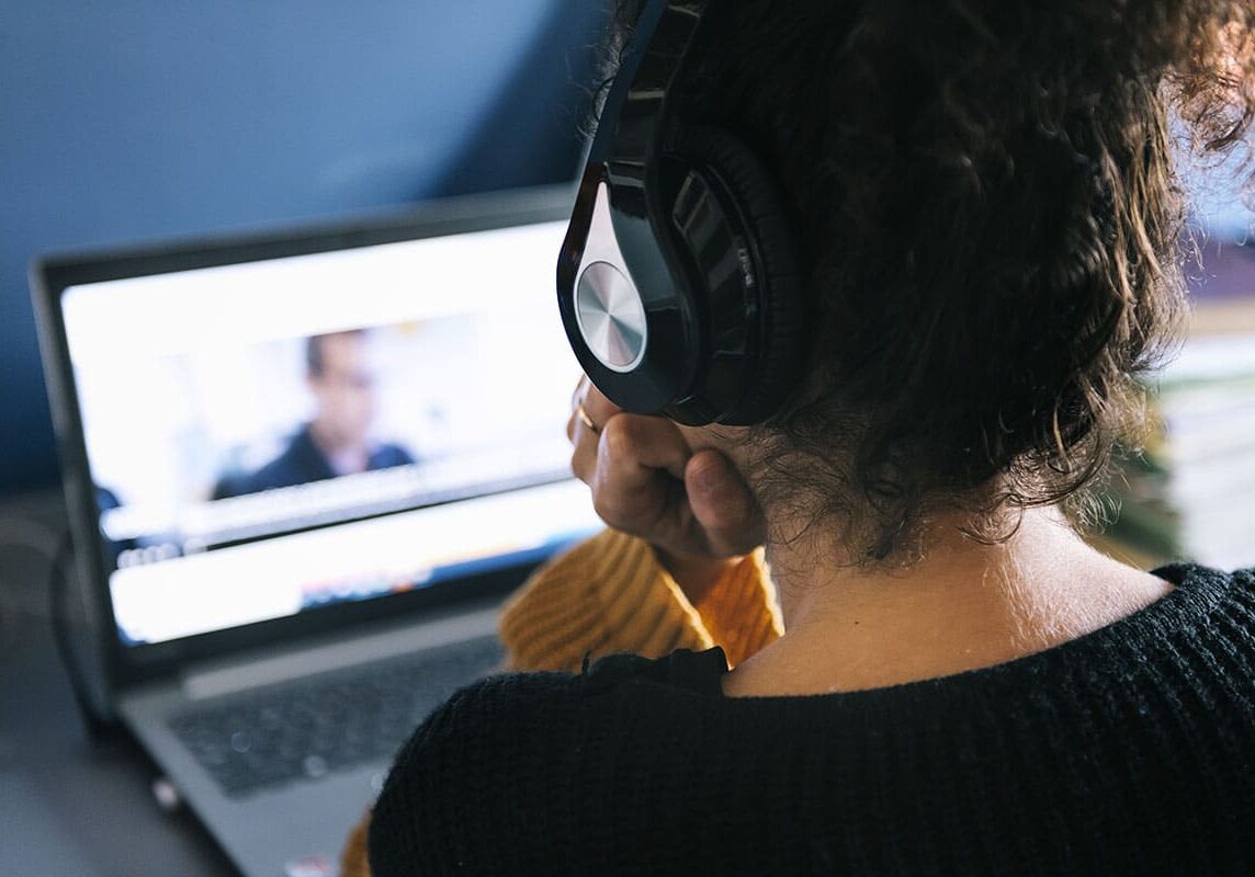 person watching video on laptop with headphones