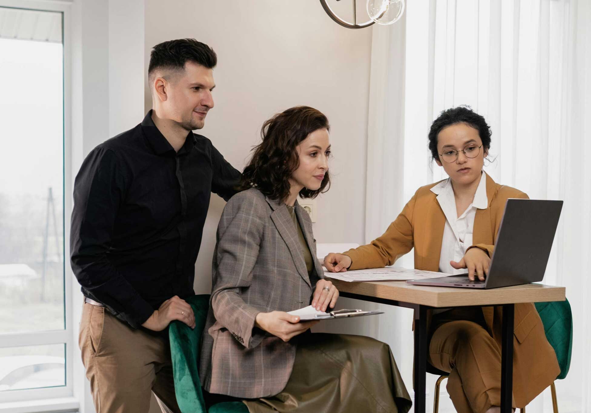 Real Estate Agent With Clients Looking At Laptop