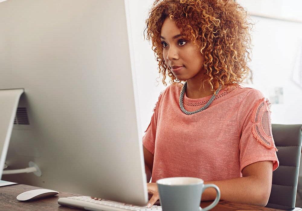 woman typing on computer with coffee